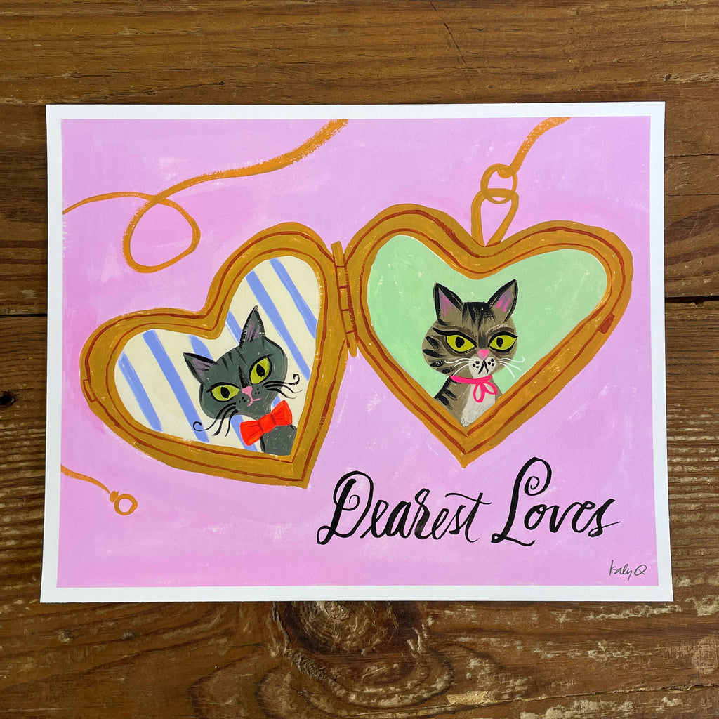 Illustration of a Russian Blue & tabby cat  inside a heart-shaped gold locket on a pink background, hand lettering reads Dearest Loves