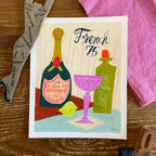 Illustration of a French 75 cocktail in a pink coupe glass with champagne and gin bottles, brush hand lettering reads French 75