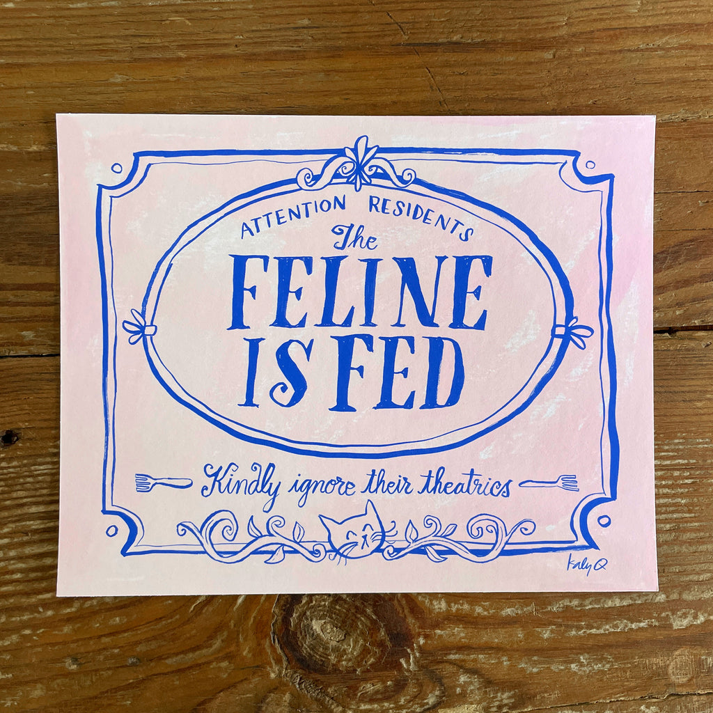Illustration of a decorative Victorian-style sign on a pale pink background, blue hand lettering reads Attention Residents: The Feline is Fed, Kindly Ignore Their Theatrics