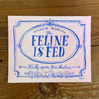 Illustration of a decorative Victorian-style sign on a pale pink background, blue hand lettering reads Attention Residents: The Feline is Fed, Kindly Ignore Their Theatrics
