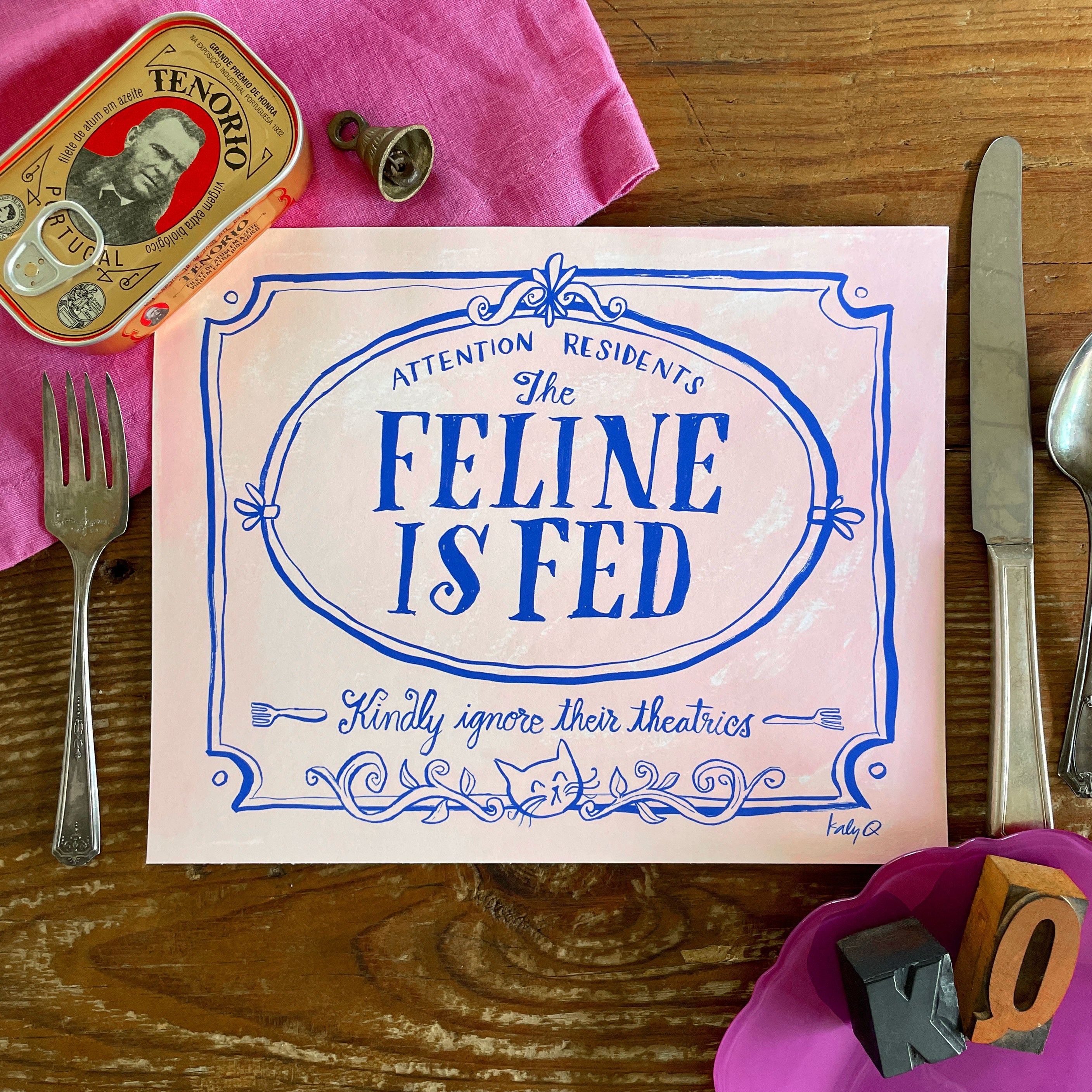 Illustration of a decorative Victorian-style sign on a pale pink background, blue hand lettering reads Attention Residents: The Feline is Fed, Kindly Ignore Their Theatrics
